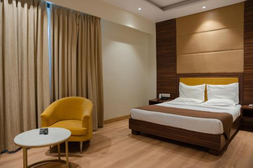 a hotel room with a bed and a chair at Hotel The Shiv Regency in Gandhidham