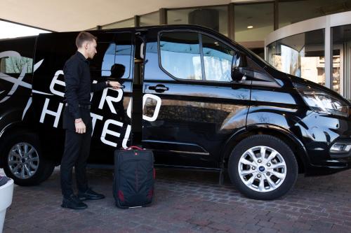 a man with a suitcase standing next to a van at Euro Hotel Residence in Concorezzo