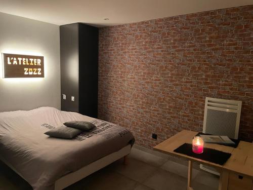 a bedroom with a bed and a brick wall at Charmant studio au cœur du pays des étangs in Langatte