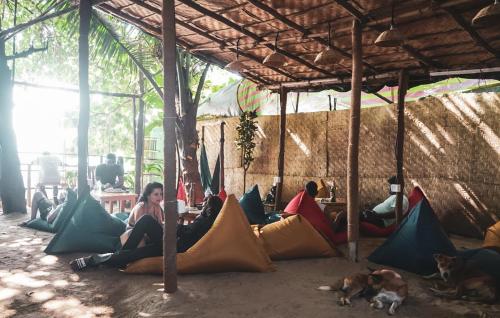 grupa ludzi siedzących pod namiotem z psami w obiekcie 12 Monks Hostel w mieście Arambol