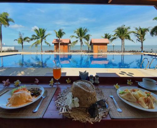 a table with plates of food next to a swimming pool at Serene Sands in Bang Lamung