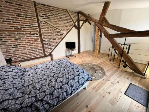 a bedroom with a bed and a brick wall at Duplex belle pierre in Digoin
