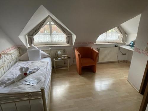 ein Schlafzimmer mit einem Bett und einem Stuhl im Dachgeschoss in der Unterkunft Hotel Friesengeist in Wiesmoor