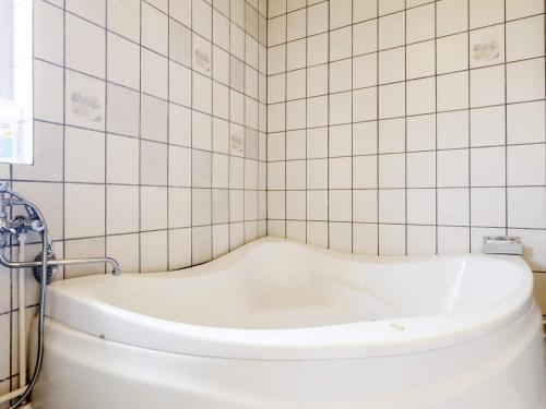 a bath tub in a bathroom with white tiles at 8 person holiday home in V ggerl se in Marielyst
