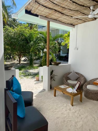 a patio with chairs and a coffee table on a beach at Bliss Dhigurah in Dhigurah