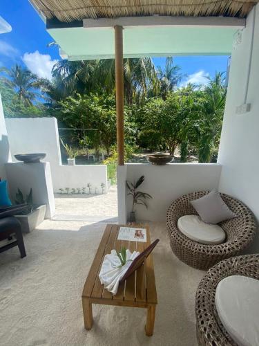 a living room with a table and a rattan chair at Bliss Dhigurah in Dhigurah