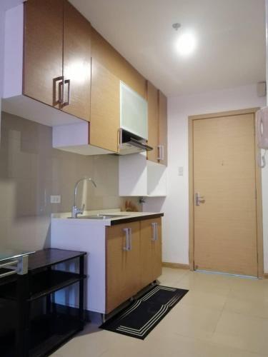 a kitchen with wooden cabinets and a sink and a door at D'University in Manila