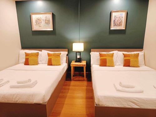 twee bedden in een kamer met een groene muur bij PloyBuri Boutique Hotel in Chanthaburi