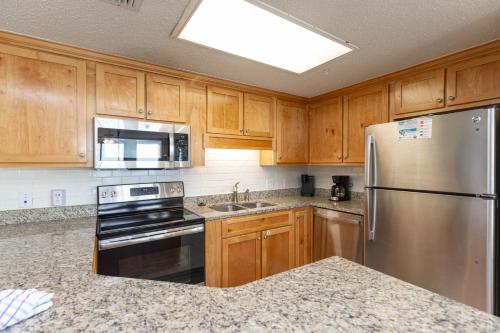 a kitchen with wooden cabinets and a stainless steel refrigerator at Phoenix X 317 in Orange Beach