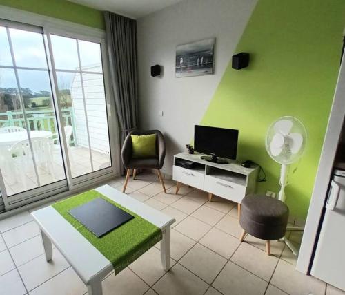 Elle comprend un salon doté d'un mur vert et d'une télévision. dans l'établissement 