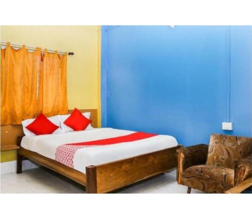 a bedroom with a bed with red pillows and a chair at Hotel Residency, Tripura in Rādhākishorepur