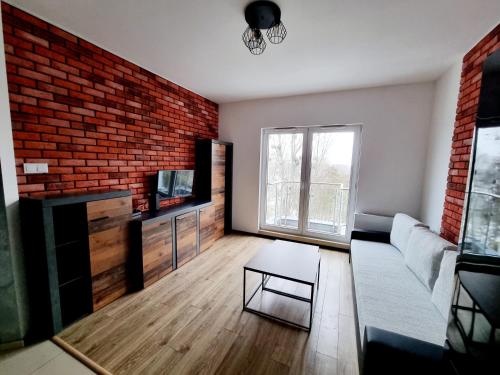 uma sala de estar com um sofá e uma parede de tijolos em Przytulny na Winnicy z widokiem na Wisłę em Toruń