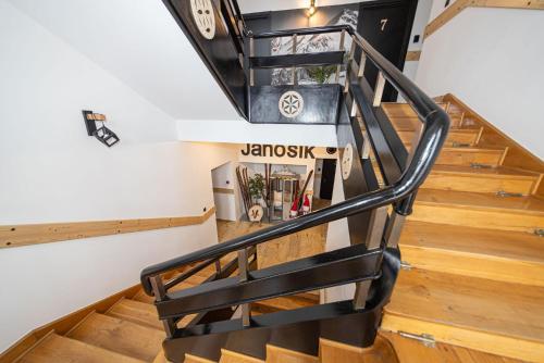 a staircase with a black rail and wood floors at Pensjonat Janosik in Zakopane