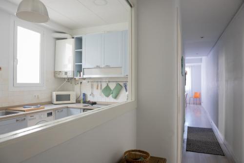 eine weiße Küche mit einer Spüle und einer Mikrowelle in der Unterkunft Seneca7 near paseo de gracia in Barcelona
