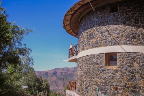 a person standing on a balcony of a stone building at Lalibela Hidmo Cozy Place in Lalibela