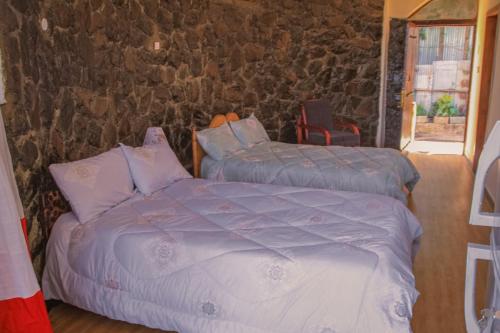 sypialnia z 2 łóżkami i kamienną ścianą w obiekcie Lalibela Hidmo Cozy Place w mieście Lalibela