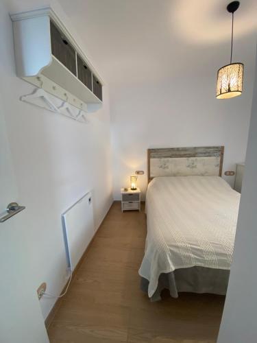 a white bedroom with a bed and a lamp at El Mirador de Llançà in Llança