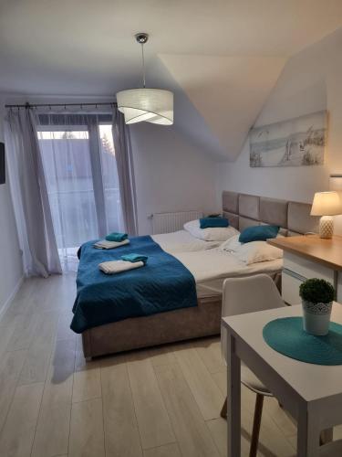 a bedroom with a bed with blue sheets and a table at ViLLA ZAKĄTEK in Grzybowo