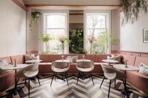 ein Restaurant mit einer langen Bank mit Tischen und Stühlen in der Unterkunft NEWLY OPENED - Parklane Hotel in Amsterdam