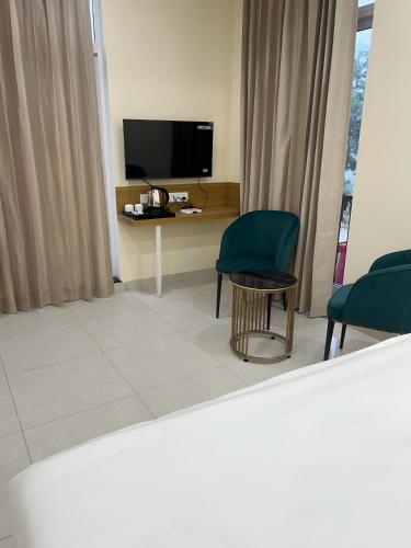 a living room with two chairs and a table with a television at The Blue Vista in Greater Noida