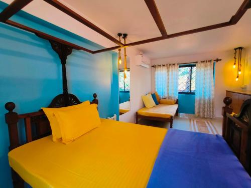 Un dormitorio con una cama amarilla y paredes azules en RiverKiss Villa en Canacona