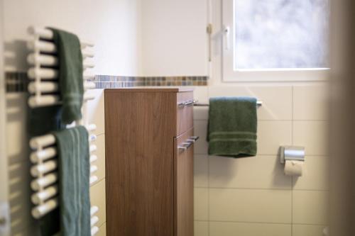 La salle de bains est pourvue de serviettes vertes et d'une fenêtre. dans l'établissement Brentschpark Wohnung C 96, à Scuol