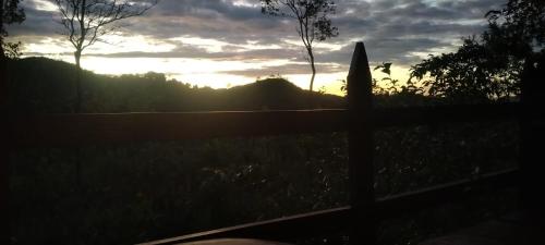 una puesta de sol sobre un campo con una valla en Kale Cottage Belihuloya en Belihul Oya