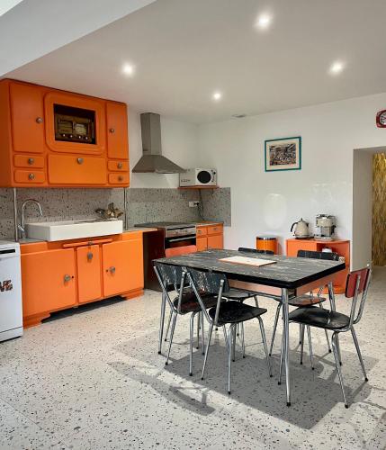 une cuisine avec des armoires orange, une table et des chaises dans l'établissement Gîte Vintage Peace & Love, à Sémussac
