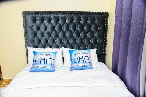 ein Bett mit zwei blauen Kissen und einem schwarzen Kopfteil in der Unterkunft Royalty Homes in Nairobi