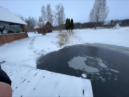 a pond in a yard with snow on the ground at Wiire old fishermans farmhouse and smoke sauna in Saulepa