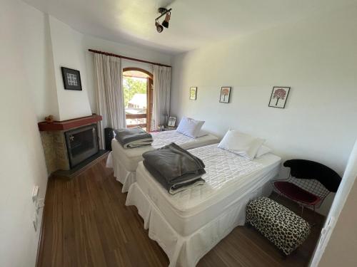 1 dormitorio con 2 camas, chimenea y silla en Quatre Saisons Residence, en Campos do Jordão