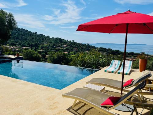 uma piscina com um guarda-sol vermelho e cadeiras ao lado de uma piscina em Villa Thalassa Art' B&B em Le Lavandou
