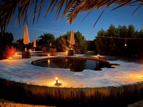 a pool with candles in the snow at night at Santarya hotel in Siwa