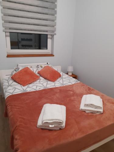 Una cama con toallas blancas y naranjas. en Przytulny Apartament na Strzeleckiej en Płock