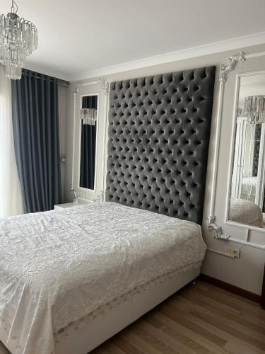 Schlafzimmer mit einem großen Bett mit einem gepolsterten Kopfteil in der Unterkunft BABİLON REZİDANS APARTMANI in Rize