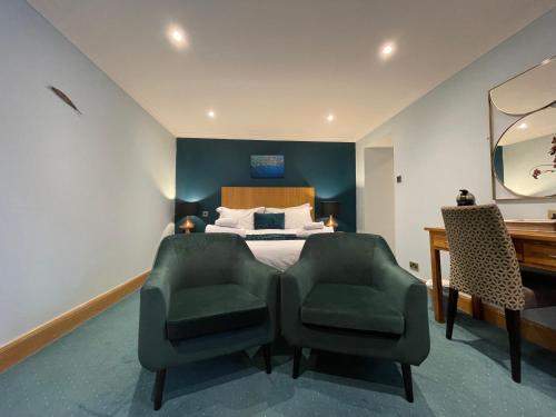 a bedroom with a bed with two chairs and a desk at The Ship Inn - Winner Best Hotel Experience 2024 Visit Scotland in Gatehouse of Fleet