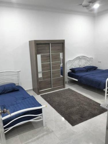 a bedroom with two beds and a cabinet and a rug at D'Parking Homestay Klia Sepang Budget Murah in Banting