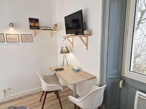 een kamer met een tafel en twee stoelen en een televisie bij "Le Bisontin", studio cosy au calme, proche de la gare in Besançon