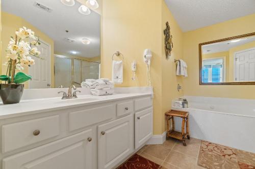 een badkamer met een wastafel, een bad en een spiegel bij Palacio 602 in Perdido Key