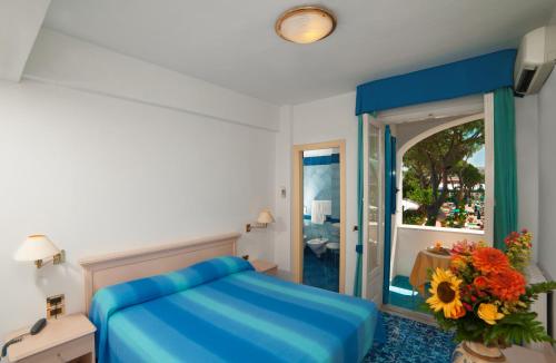 a bedroom with a blue bed and a mirror at Hotel Villa Hermosa in Ischia
