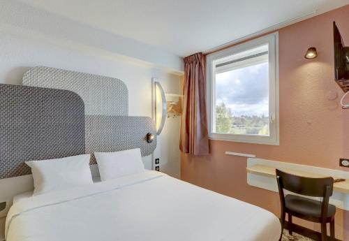 Pokój z łóżkiem, biurkiem i oknem w obiekcie B&B HOTEL Montluçon Saint-Victor w mieście Saint-Victor