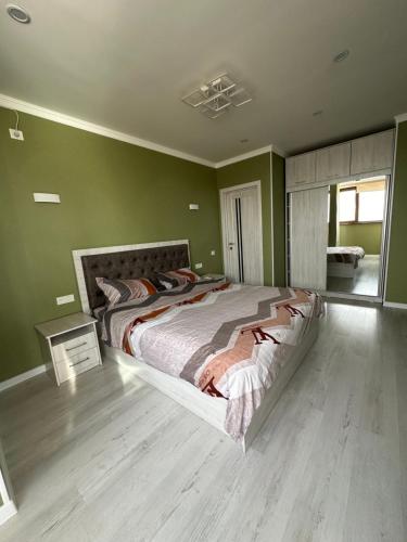a bedroom with a large bed with green walls at The nest above the clouds in Yakkasaray