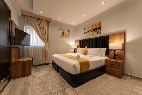 a bedroom with a large bed and a flat screen tv at Andalus Habitat Hotel in Jeddah