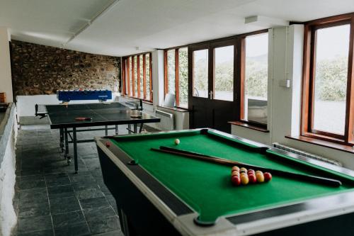 a billiard room with two pool tables and windows at Treleddyn Farmhouse in St. Davids