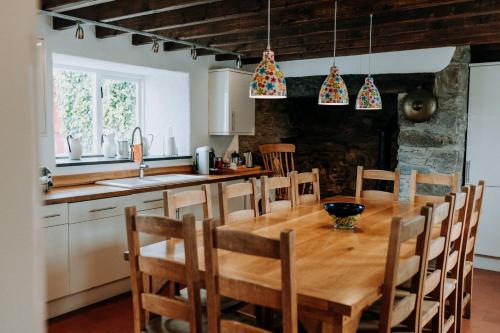 a kitchen with a wooden table and chairs in a room at Treleddyn Farmhouse in St. Davids