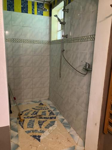 um chuveiro na casa de banho com piso em azulejo em Kazamwe em Petit-Bourg