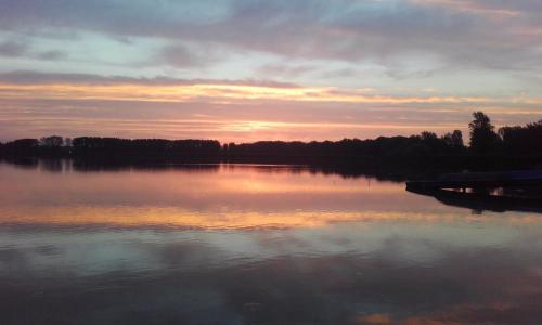 een uitzicht op een meer met zonsondergang bij Lakeside Apartmanház Soltvadkert in Soltvadkert