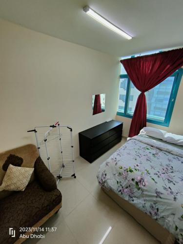 a bedroom with a bed and a chair and a window at Bedroom 4 in Abu Dhabi