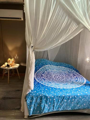 a bed with a canopy with a blue and white comforter at Kazamwe in Petit-Bourg
