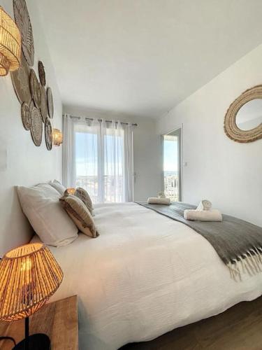 une chambre blanche avec un grand lit et une fenêtre dans l'établissement L'horizon Cathare - Sublime vue Cité Médiévale, à Carcassonne